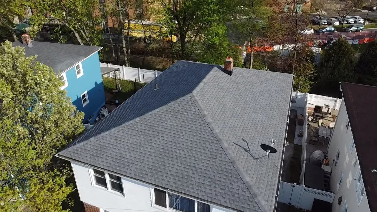 Drone aerial view of a completed dark grey hip roof with new asphalt shingles after full roof replacement in New Jersey