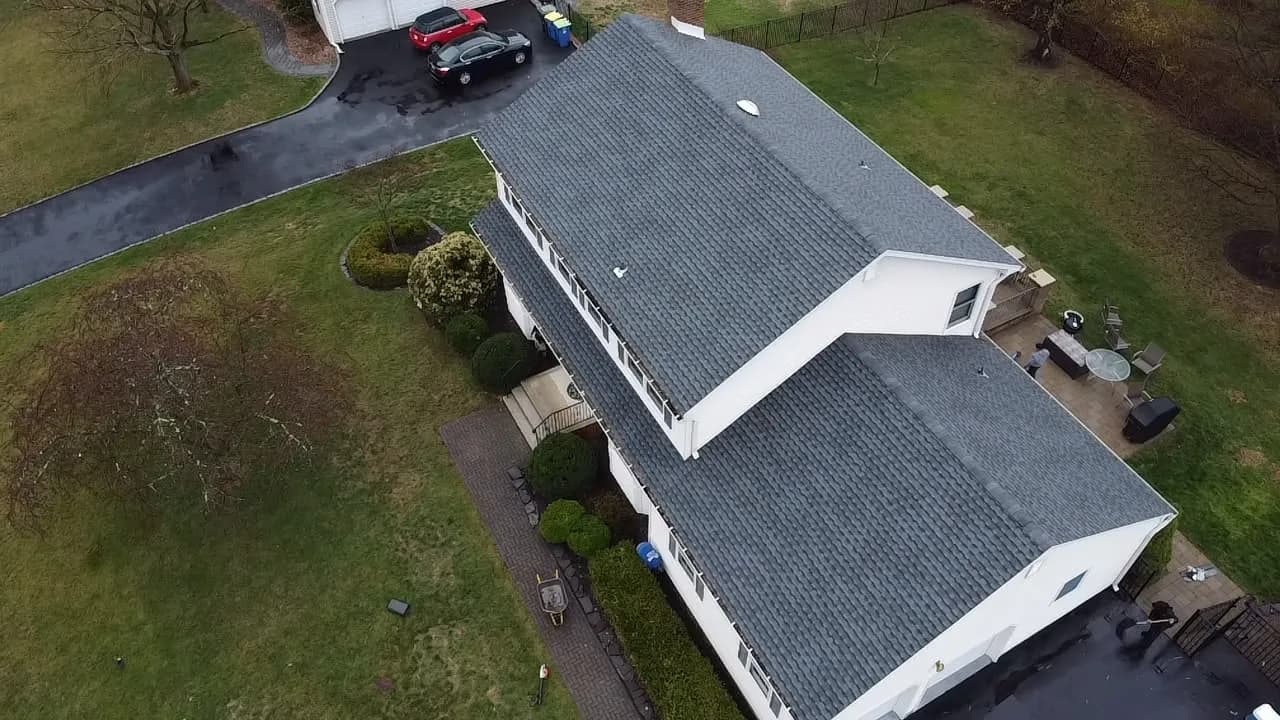 Aerial view of a completed multi-gable roof with dark charcoal architectural shingles after full replacement in New Jersey